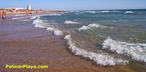 Vista de la playa de El Palmar, en el horizonte se puede ver la torre viga de El Palmar, Torre Nueva, la cual se encuentra al lado de un restaurante.